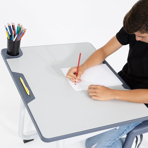 Criança a desenhar numa folha de papel numa mesa Ergos Edge, com lápis de cor junto ao desenho.