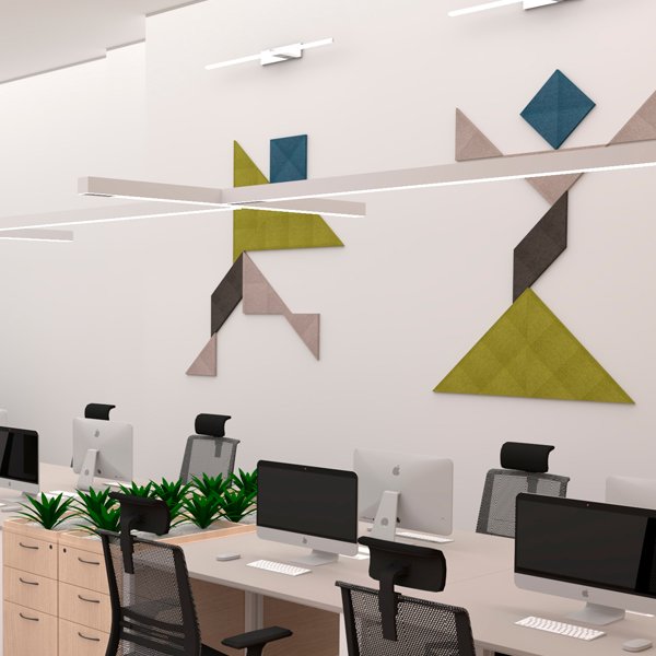 Escritório com mesas, computadores, cadeiras, plantas e painéis geométricos de várias cores na parede.