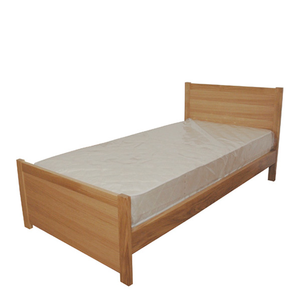 Cama individual de madeira com cabeceira, peseira e colchão protegido por plástico.