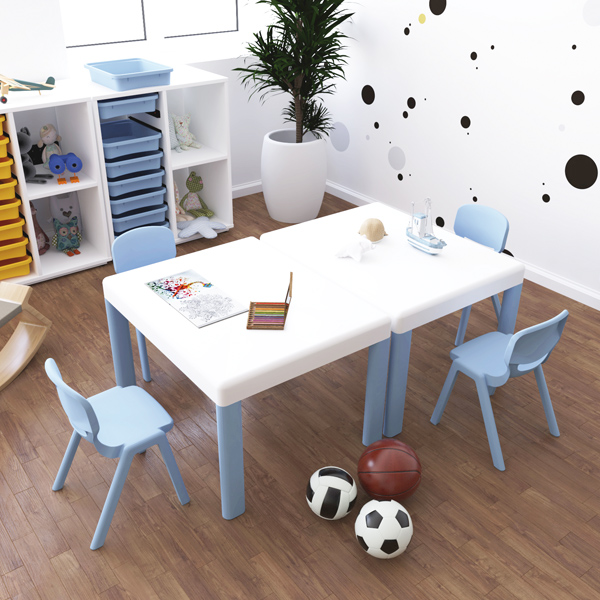 Sala de actividades com mesas, cadeiras azuis, livros, brinquedos e materiais de desenho.