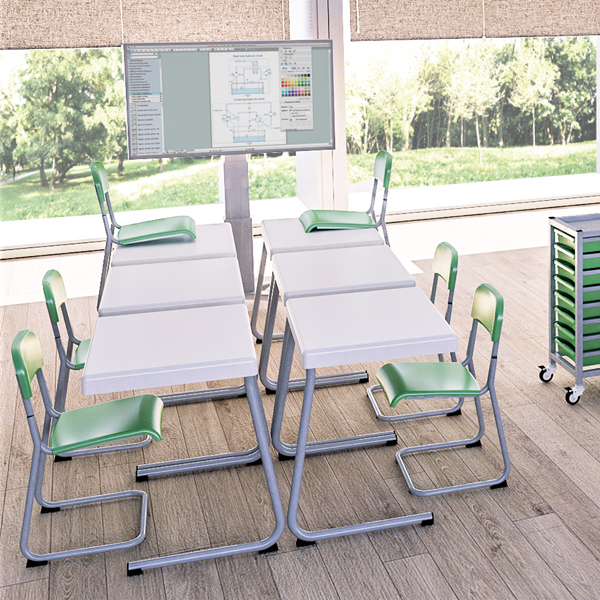 Sala de aula com mesas brancas, cadeiras verdes e brancas, um ecrã e grandes janelas.