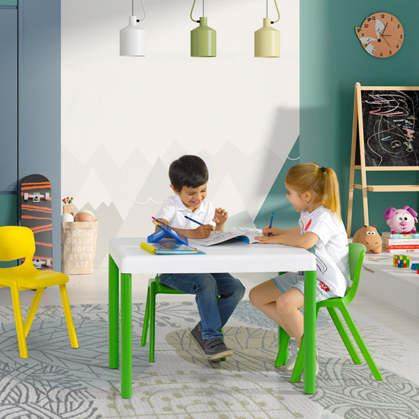 Duas crianças desenham e pintam numa mesa, numa sala com cadeiras de várias cores e brinquedos.