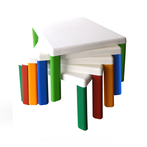 Mesas para o pré-escolar empilhadas, com tampos brancos e pernas de várias cores.