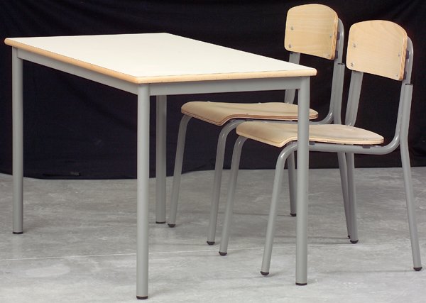 Mesa escolar dupla de tampo claro acompanhada de duas cadeiras de madeira com estruturas metálicas.