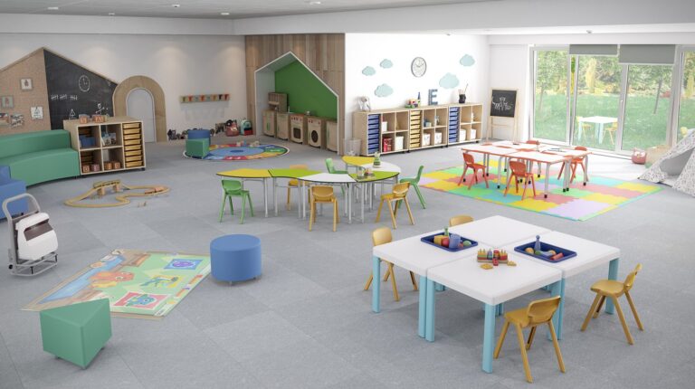 Sala do pré-escolar com mesas, cadeiras, tapetes e estantes com brinquedos, organizada em zonas de actividades.