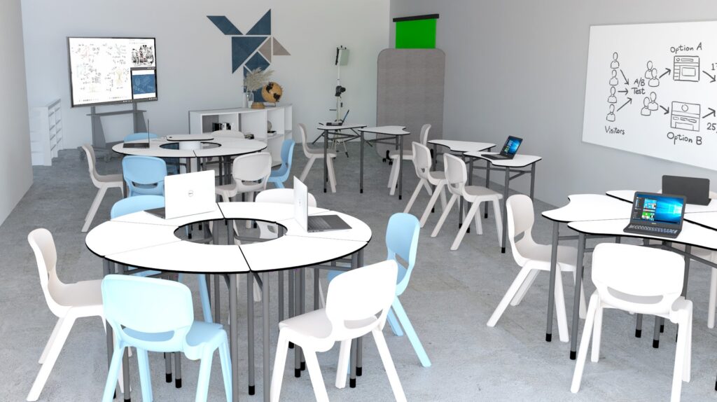 Sala de aula com mesas brancas agrupadas, cadeiras azuis e brancas, computadores portáteis, quadro e ecrã digital.