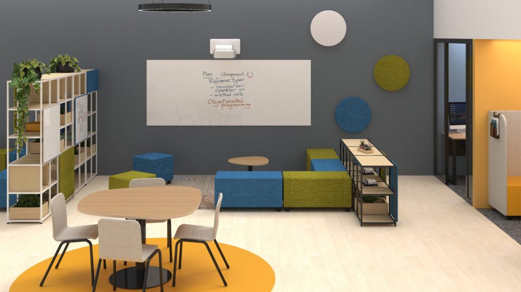 Espaço de trabalho com assentos azuis e verdes, quadro com anotações, painéis redondos e mesa de reunião.