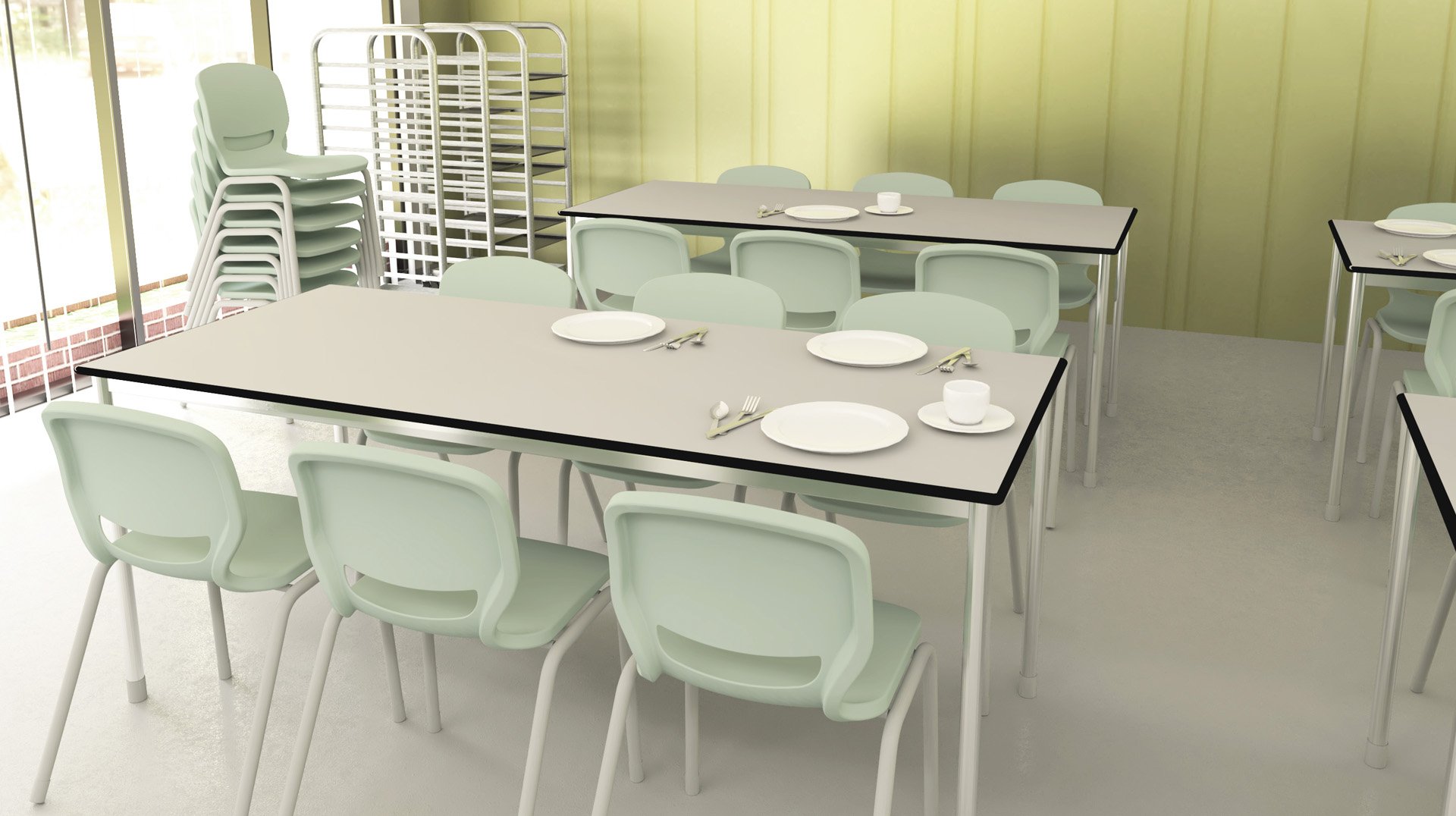 Una cafetería con sillas verde menta y mesas con platos, tazas y cubiertos. Al fondo hay pilas de sillas y bandejas metálicas cerca de grandes ventanales y una pared de color amarillo pálido. La sala parece limpia y vacía.
