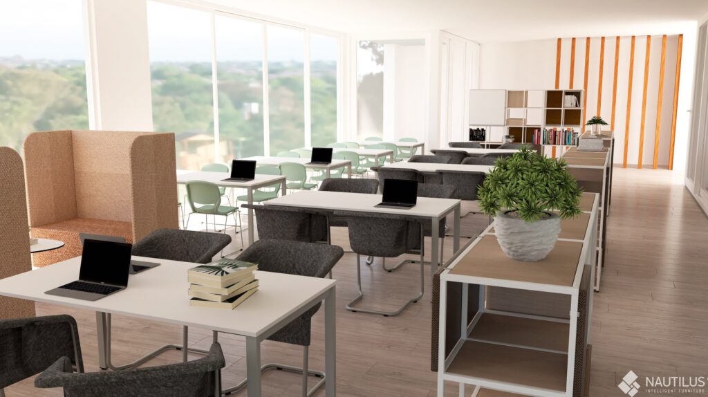 Sala de professores com mesas, computadores portáteis, cadeiras, livros e estante.
