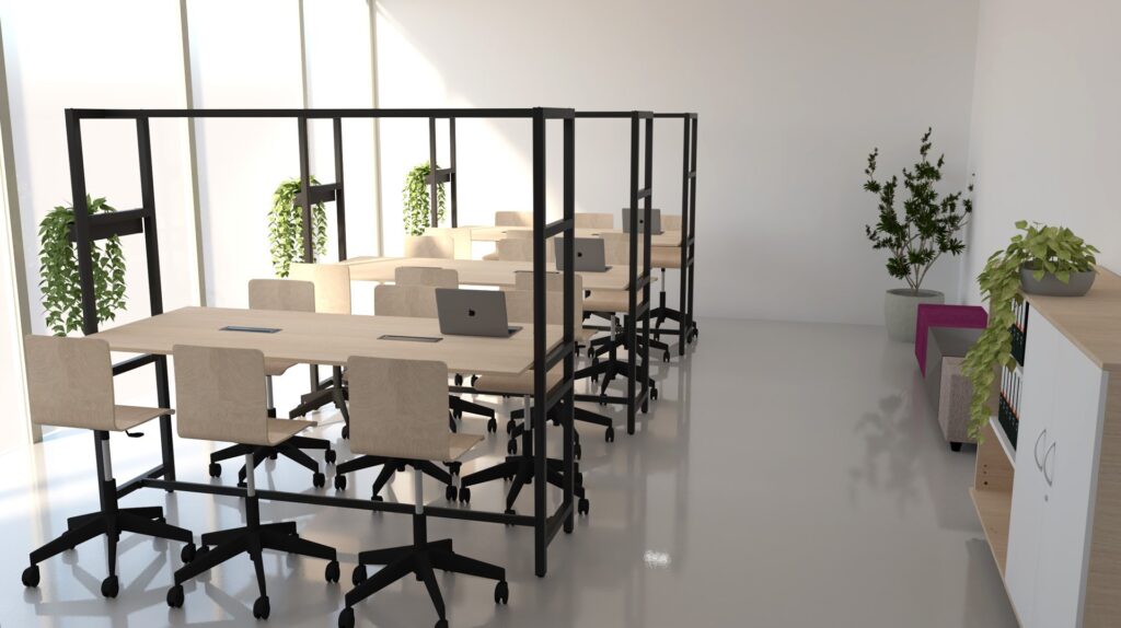 Sala de professores com mesas de trabalho, computadores portáteis, plantas e zona de estar com sofá.