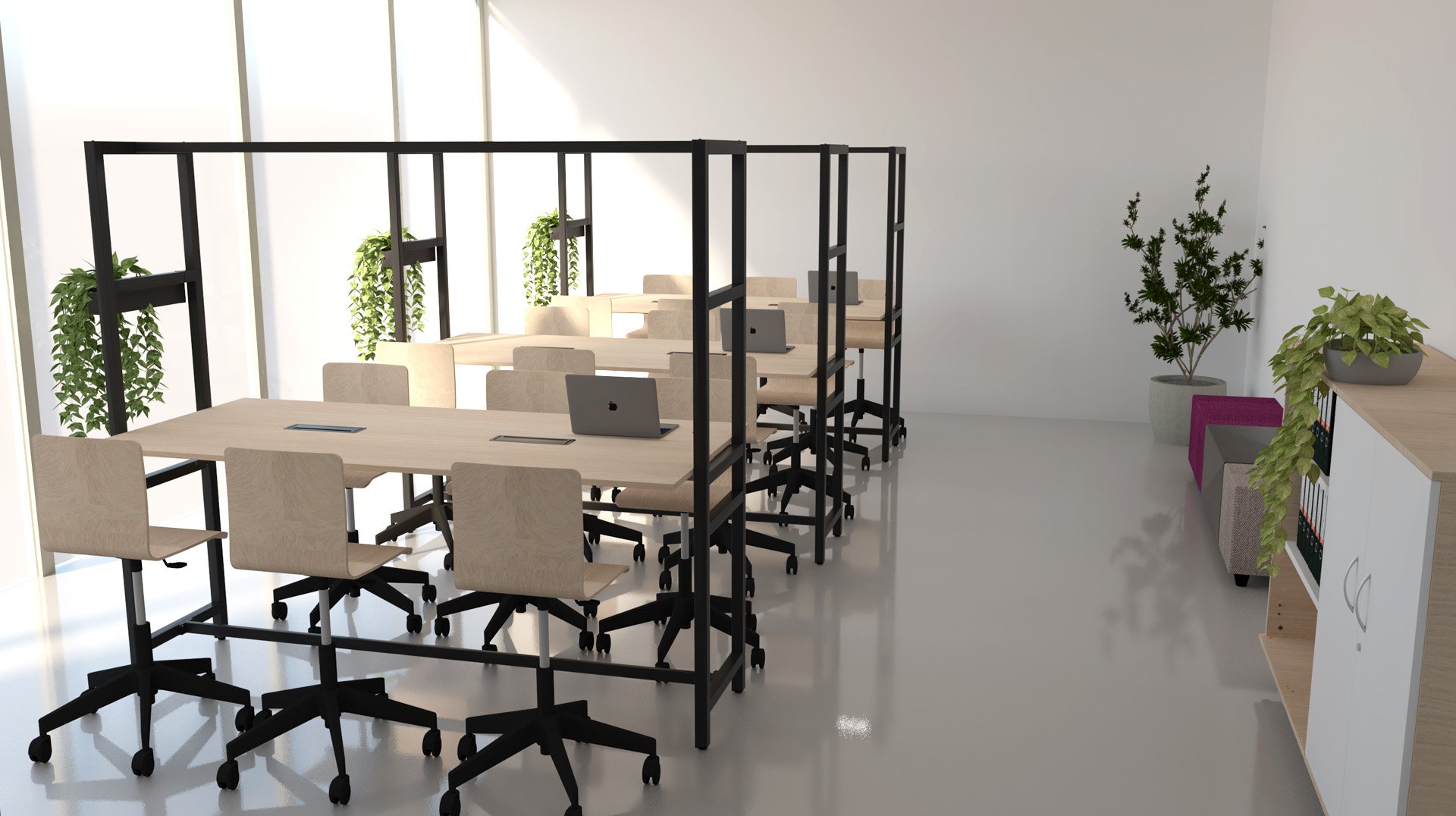 Sala de professores com mesas de trabalho, computadores portáteis, plantas e zona de estar com sofá.