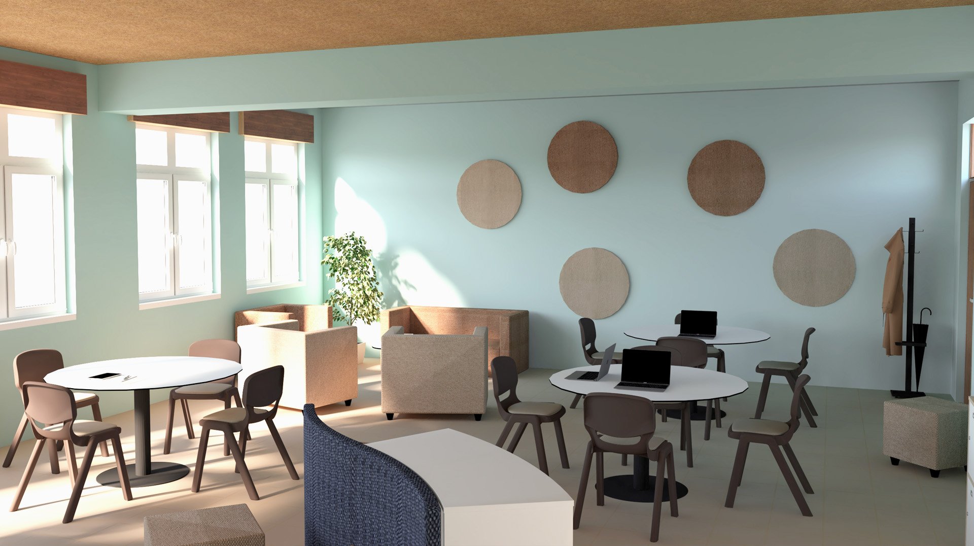 Sala de professores com mesas redondas, cadeiras cinzentas, cadeirões bege e computadores portáteis.