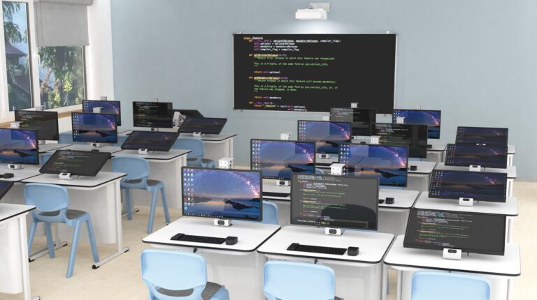 Sala de informática com computadores a mostrar código, cadeiras azuis e projecção de instruções de programação.