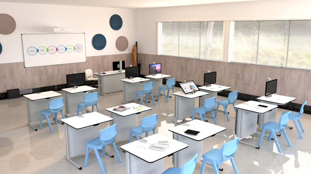 Sala de aula com mesas brancas em filas, cadeiras azuis, computadores portáteis e tablets.