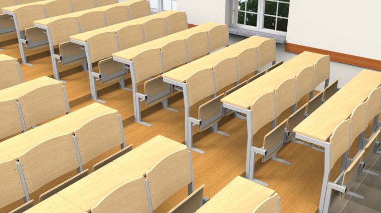 Sala com mesas e cadeiras de madeira dispostas em filas.
