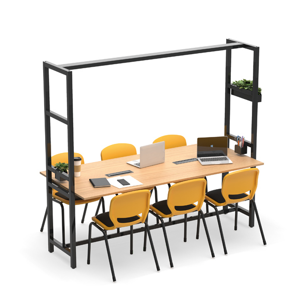 Una mesa rectangular con seis sillas amarillas y un armazón de metal negro encima, que sostiene pequeñas plantas. El tablero de la mesa tiene tres ordenadores portátiles abiertos, cuadernos, smartphones y útiles de escritura.