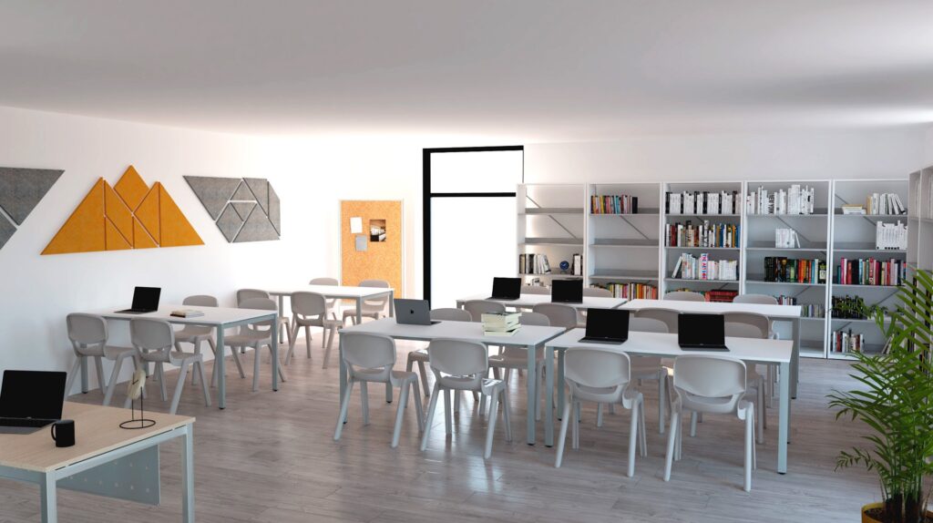 Sala com mesas e cadeiras brancas, computadores portáteis, estantes com livros e decoração geométrica.