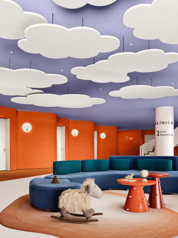Sala com paredes laranja, assentos curvos azuis, mesas vermelhas e elementos em forma de nuvem suspensos no tecto.