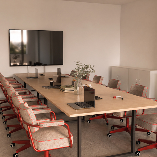Sala de reunião com mesa comprida, cadeiras de braços e ecrã grande na parede.