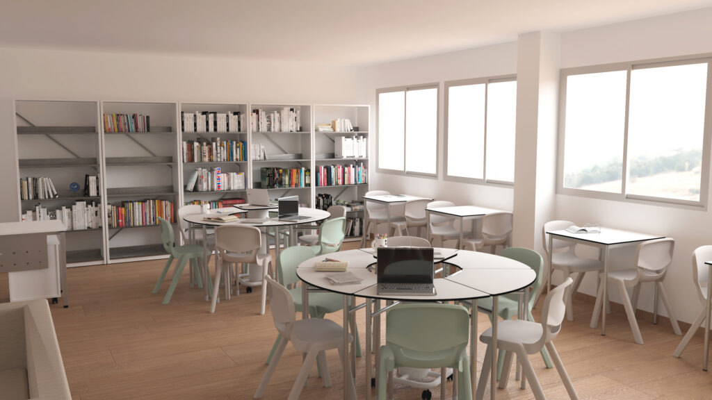 Espaço de leitura com mesas redondas, cadeiras, computadores portáteis e estantes com livros.