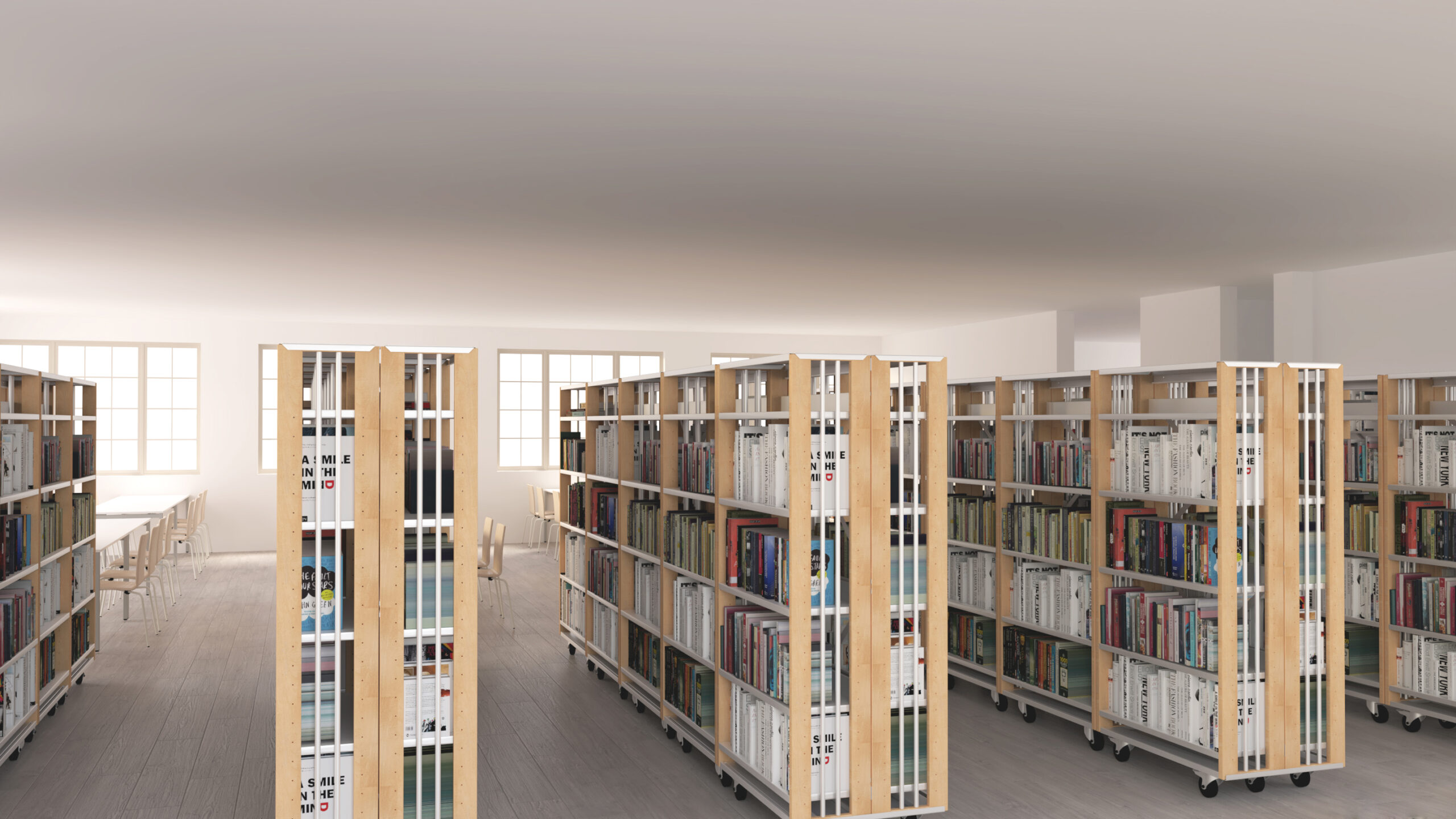 Biblioteca com estantes de livros em filas e mesas de leitura junto às janelas.