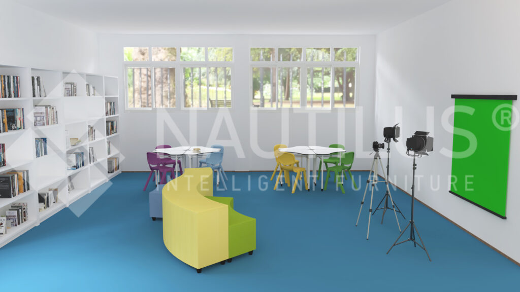 Sala com pavimento azul, estantes brancas, mesas, cadeiras de várias cores e equipamento de vídeo com fundo verde.