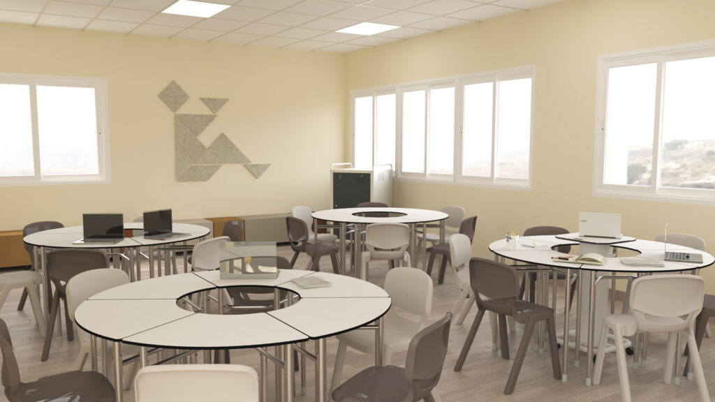 Sala com mesas redondas, cadeiras cinzentas, computadores portáteis e livros.
