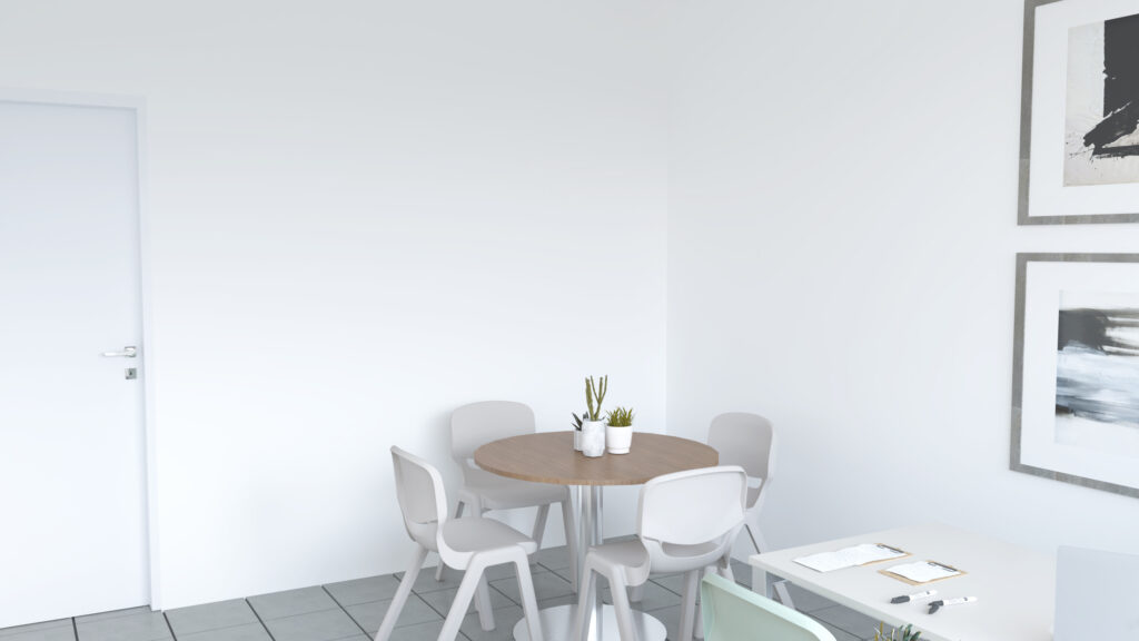 Sala com mesa redonda de madeira, cadeiras brancas e uma mesa de trabalho com documentos.