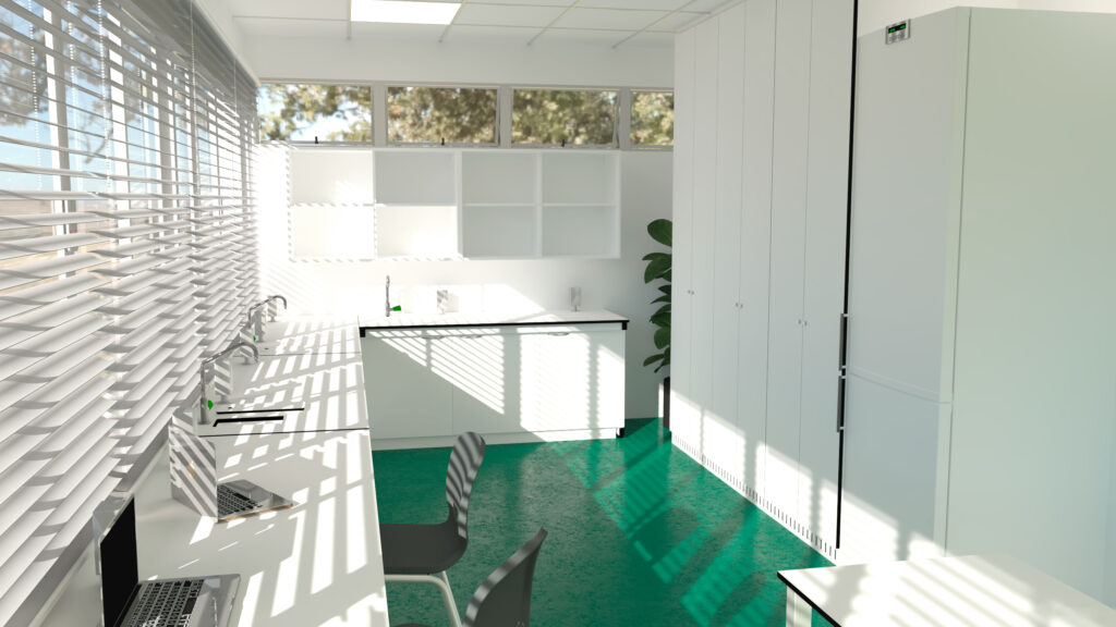 Sala de trabalho com pavimento verde, armários, estantes e computadores portáteis junto às janelas.