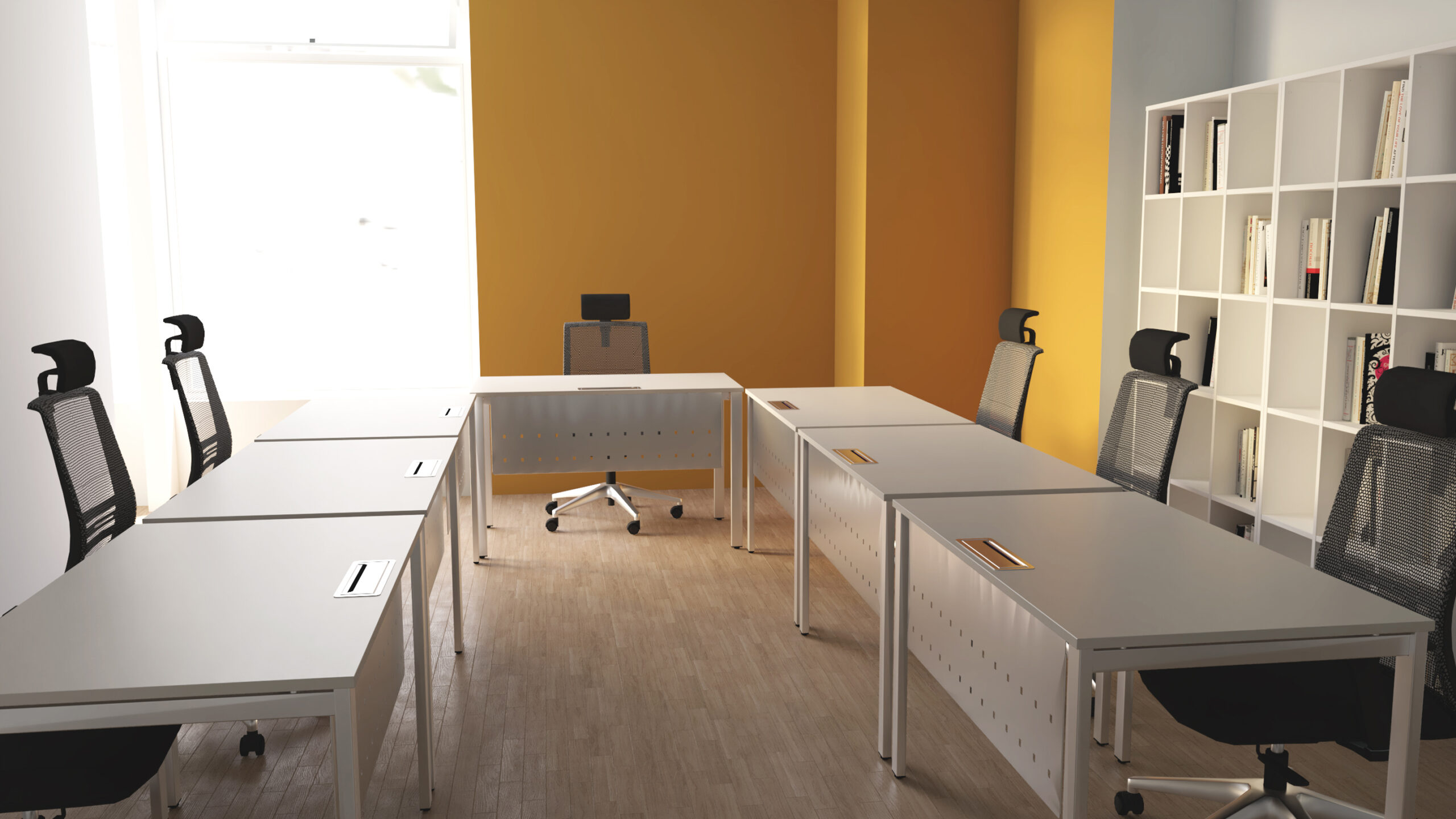 Espaço de trabalho com mesas dispostas em U, cadeiras pretas e estante branca junto a paredes amarelas.