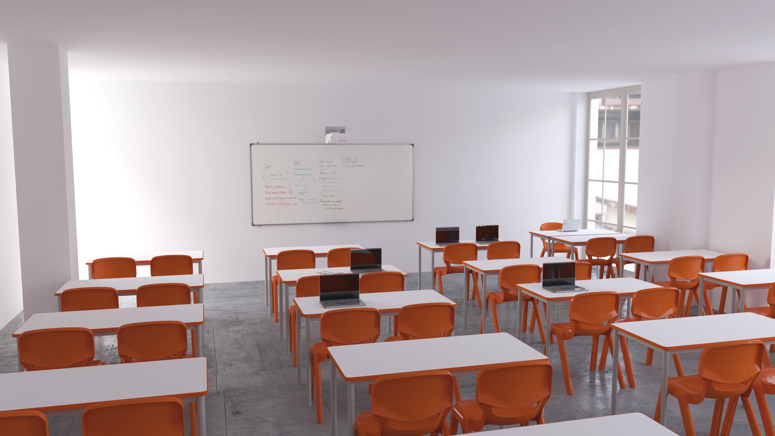 Sala de aula com mesas brancas em filas, cadeiras laranja e computadores portáteis.
