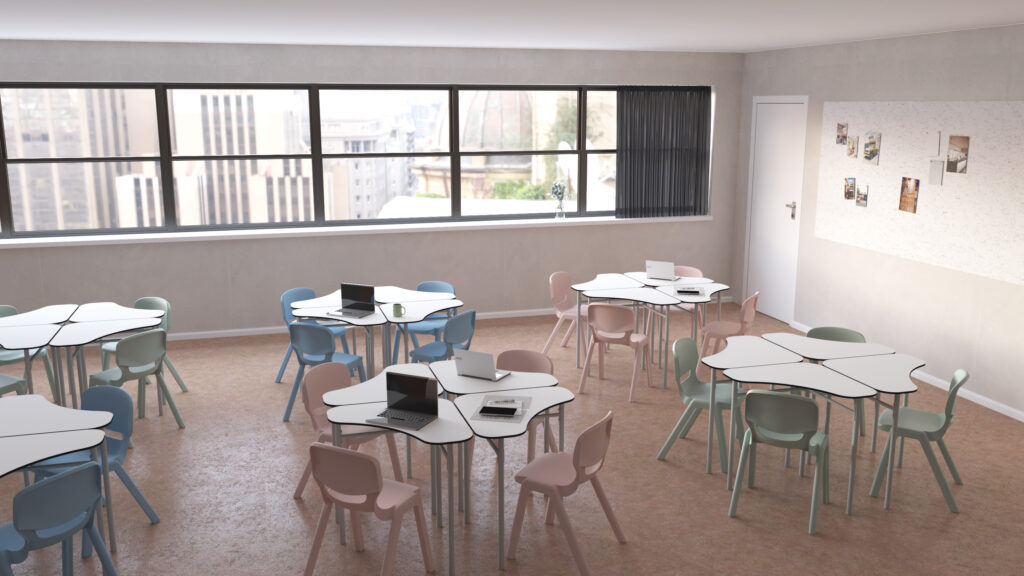 Sala com mesas hexagonais, cadeiras em tons pastel, computadores portáteis e painel com fotografias.