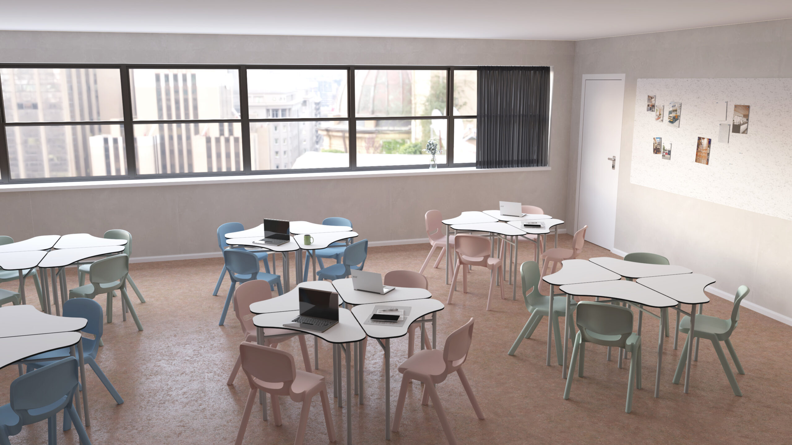 Sala com mesas hexagonais, cadeiras em tons pastel, computadores portáteis e painel com fotografias.