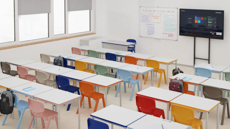 Sala de aula com mesas brancas, cadeiras de v&aacute;rias cores, mochilas, quadro e ecr&atilde; na parede.